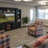 Comfortable lounge area with plaid armchairs, sofa seating, a large media cabinet, and windows providing natural light.
