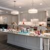 Spacious community kitchen with a large island set with desserts and beverages, white cabinetry, and stainless steel appliances.