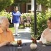 Two women enjoying lunch and conversation at an outdoor patio table surrounded by greenery.