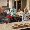 Group of older adults socializing at a bar area, enjoying drinks and conversation in a community setting.