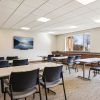 Bright meeting room with tables and chairs, large windows, and a wall-mounted TV in a modern community space.