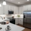 Modern kitchen with white cabinets, stainless steel appliances, quartz countertops, and pendant lighting.