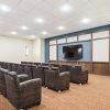 Modern community theater room with rows of comfortable chairs facing a large screen.