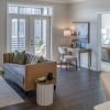 Bright living room with modern sofa, glass coffee table, large windows, and balcony access with natural light.