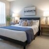 Modern staged bedroom with neutral decor, upholstered bed, bedside lamps, and soft natural light from large window.