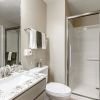 Modern bathroom with granite vanity countertop, walk-in glass shower, and neutral finishes.