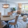 Elegant open-concept dining and living room with modern lighting, wood flooring, and large windows.