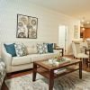 Stylish open-concept living and dining room with patterned accent chairs, wood flooring, and adjacent kitchen.