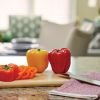 Fresh bell peppers on a kitchen countertop with modern open-concept living area in the background.