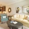 Spacious open-concept living room with cream sofa, accent chairs, and modern kitchen with granite countertops and stainless-steel appliances.