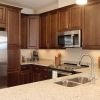 Modern apartment kitchen with dark wood cabinetry, granite countertops, stainless steel appliances, and pendant lighting.
