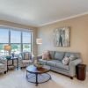 Cozy apartment living room with large window, gray sofa, patterned accent chairs, and natural light.
