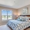 Bright bedroom with floral bedding, large window, wood furniture, and soft neutral decor. 
