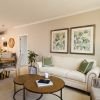 Open-concept living and dining room with neutral decor, comfortable seating, and adjacent modern kitchen.