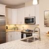 Bright kitchen with white cabinetry, granite countertops, stainless steel appliances, and pendant lighting.