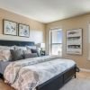 Modern bedroom with gray bedding, large windows, neutral decor, and contemporary furniture.