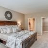 Spacious primary bedroom with wood furniture, neutral decor, plush carpeting, and walk-in closet access.