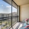 Screened-in apartment balcony with seating area, neighborhood views, and natural sunlight.