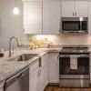 Bright modern kitchen with white cabinetry, granite countertops, stainless steel appliances, and wood flooring. 