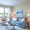 Bright and cozy living room with large picture window, soft seating, and neutral modern decor.