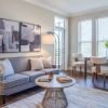 Modern living and dining area with contemporary furniture, wood flooring, and abundant natural light. 