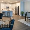 Modern open-concept apartment with dining area, contemporary seating, and bright white kitchen with island. 
